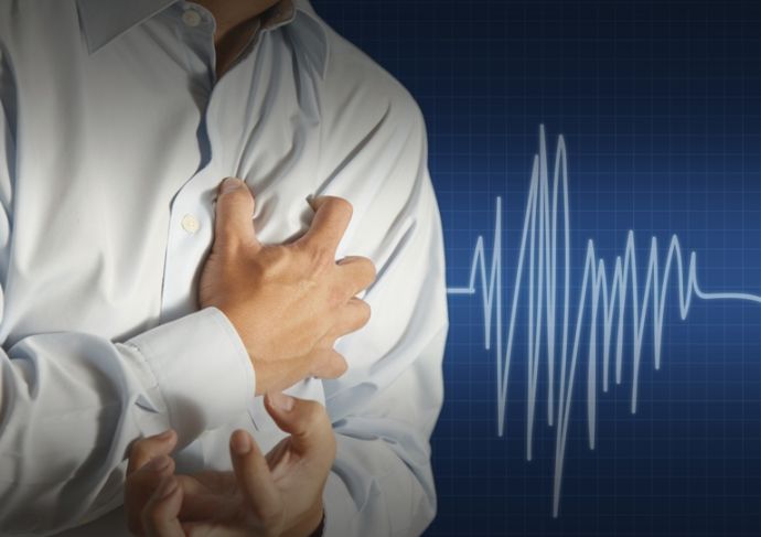 Man gripping his chest with his vital signs showing a heart attack.