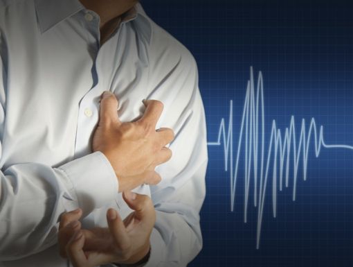 Man gripping his chest with his vital signs showing a heart attack.
