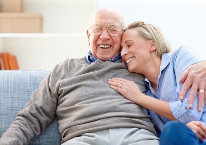 older man and woman hugging on couch smiling