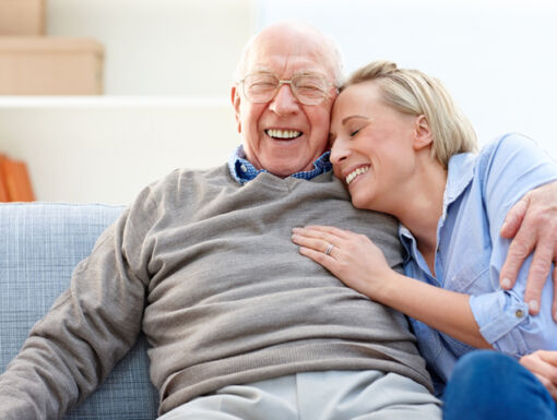 older man and woman hugging on couch smiling