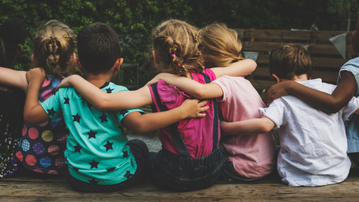 a group of children sitting on a bench hugging