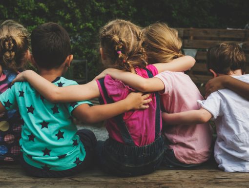 a group of children sitting on a bench hugging