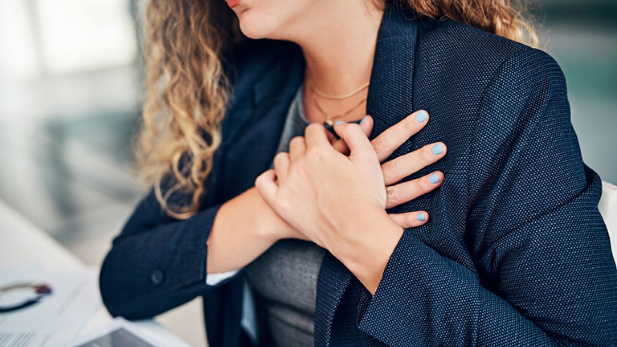 Women sitting at her desk with her hands folded over her heart