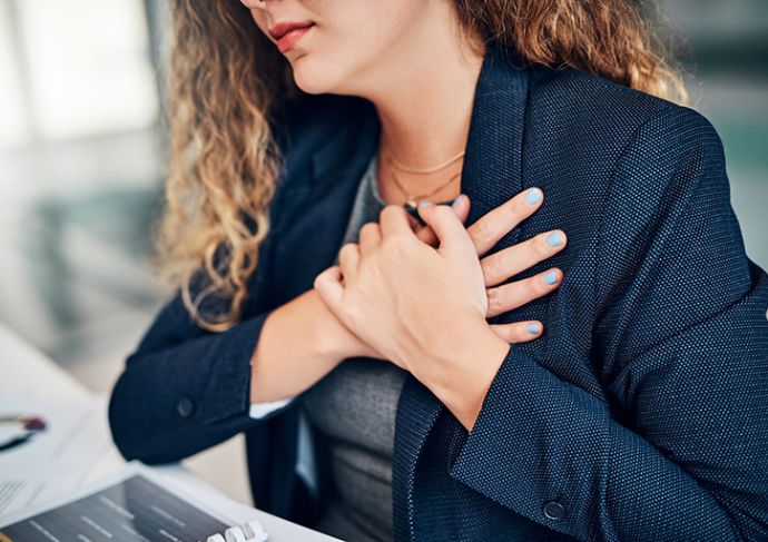 Women sitting at her desk with her hands folded over her heart