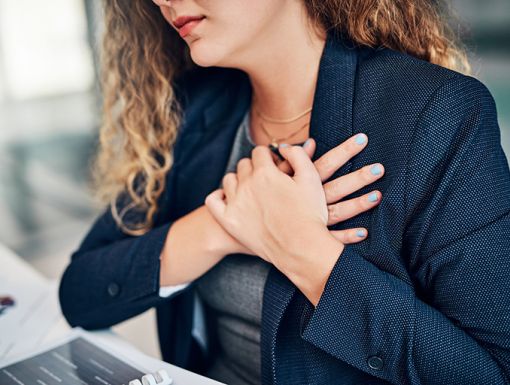 Women sitting at her desk with her hands folded over her heart