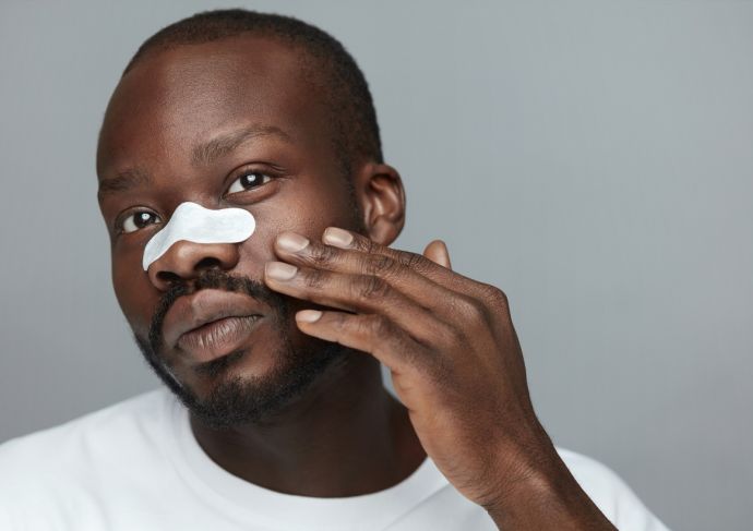 Man Applying White pore strip to nose