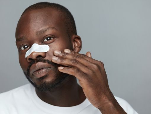 Man Applying White pore strip to nose