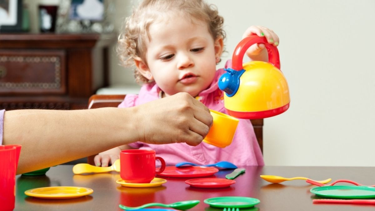 little girl playing with plastic tea set