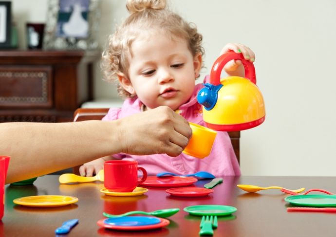 little girl playing with plastic tea set