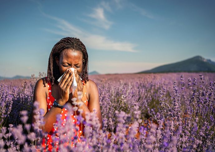 Woman in flower field sneezing