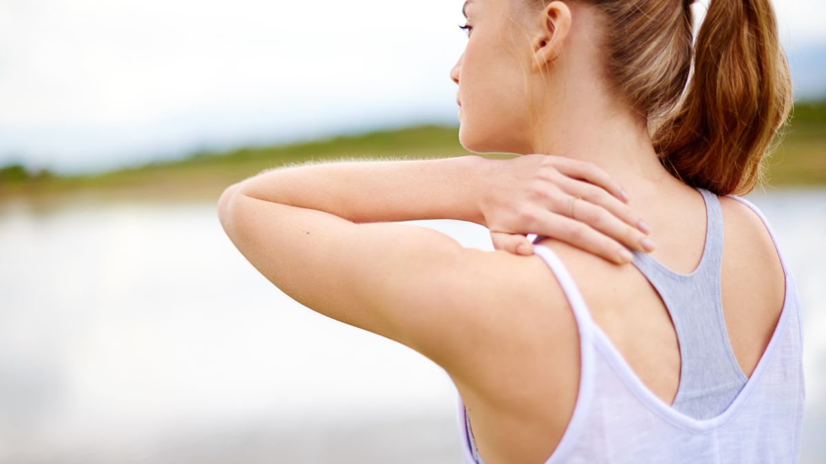 woman experiencing shoulder pain with hand on back