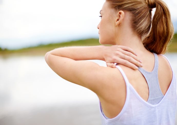 woman experiencing shoulder pain with hand on back