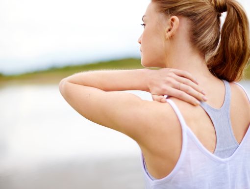 woman experiencing shoulder pain with hand on back