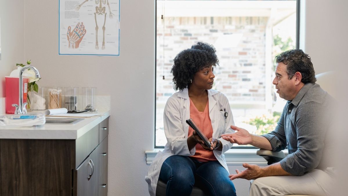 Female physcian speaking with male patient in doctor's office