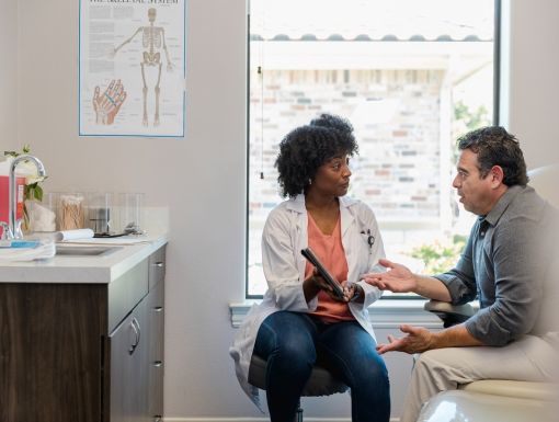 Female physcian speaking with male patient in doctor's office