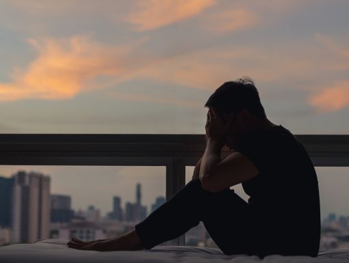 A man sitting and feeling depressed on bed