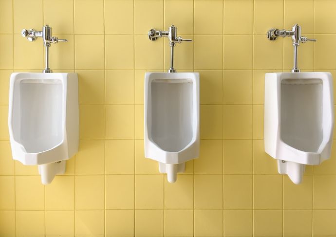 Row of white urinals on yellow of wall public toilet