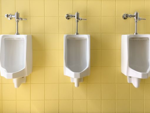 Row of white urinals on yellow of wall public toilet