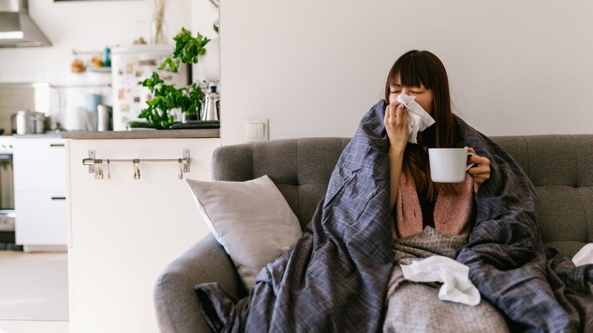Woman blowing nose on couch
