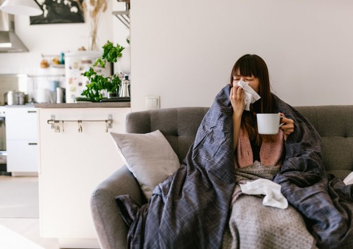 Woman blowing nose on couch