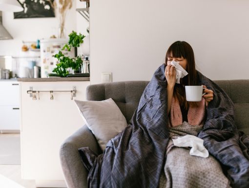 Woman blowing nose on couch
