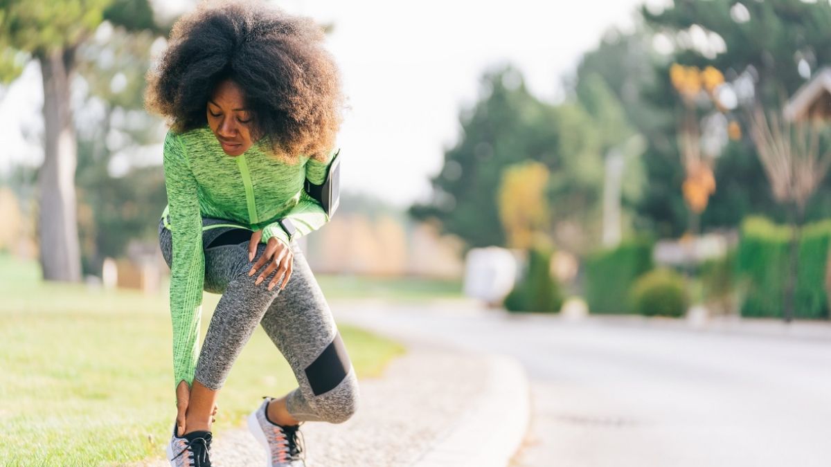 Woman grabbing ankle after stopping in the middle of run