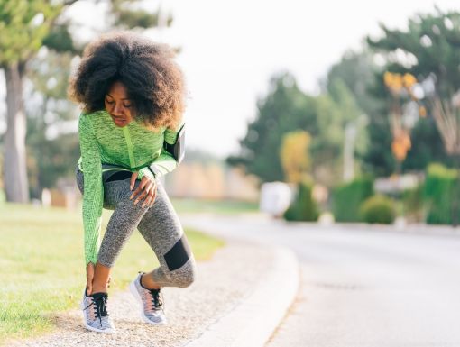 Woman grabbing ankle after stopping in the middle of run