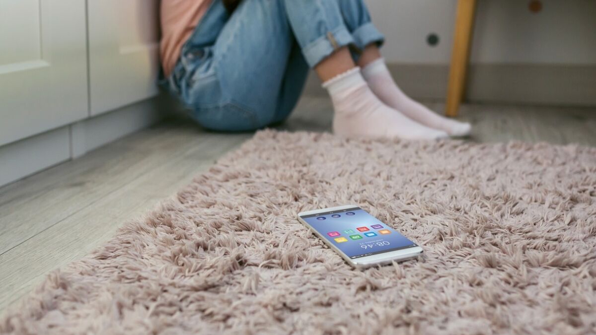 Teen on the floor with cell phone in corner