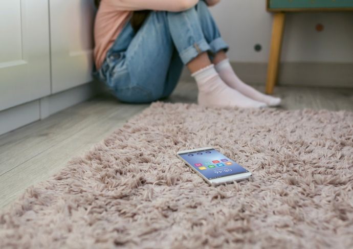 Teen on the floor with cell phone in corner