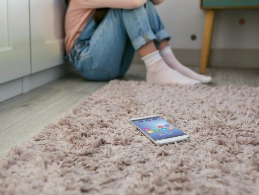 Teen on the floor with cell phone in corner