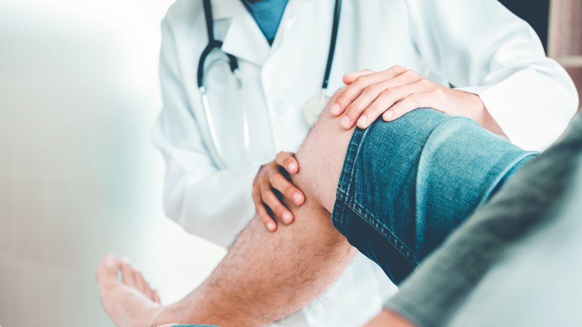 Doctor examining man's knee for replacement surgery