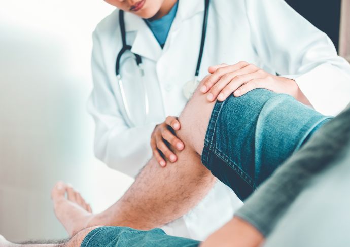 Doctor examining man's knee for replacement surgery
