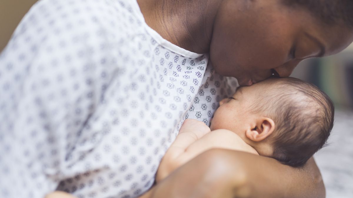 mother in hospital gown kissing newborn