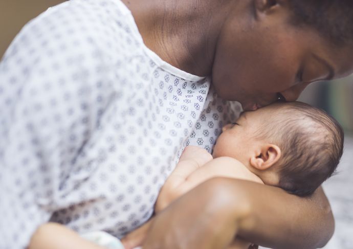 mother in hospital gown kissing newborn