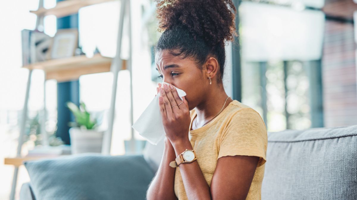 Woman with allergies sneezing into tissue