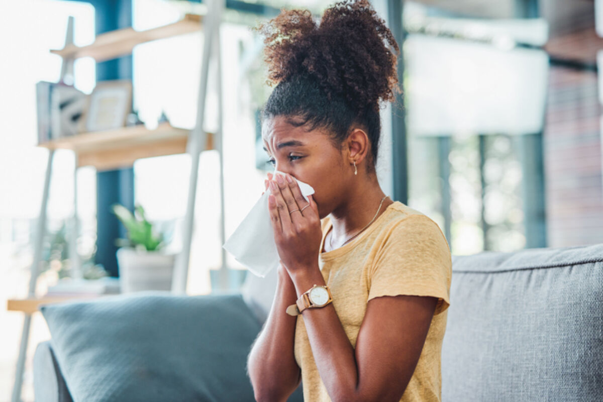 Woman with allergies sneezing into tissue