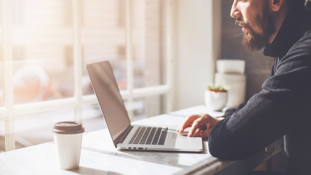 man on laptop near window
