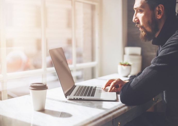 man on laptop near window