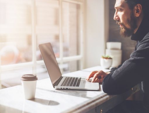 man on laptop near window