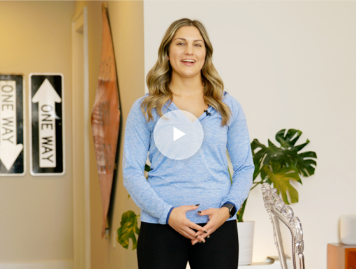 Woman standing indoors talking at camera with play button