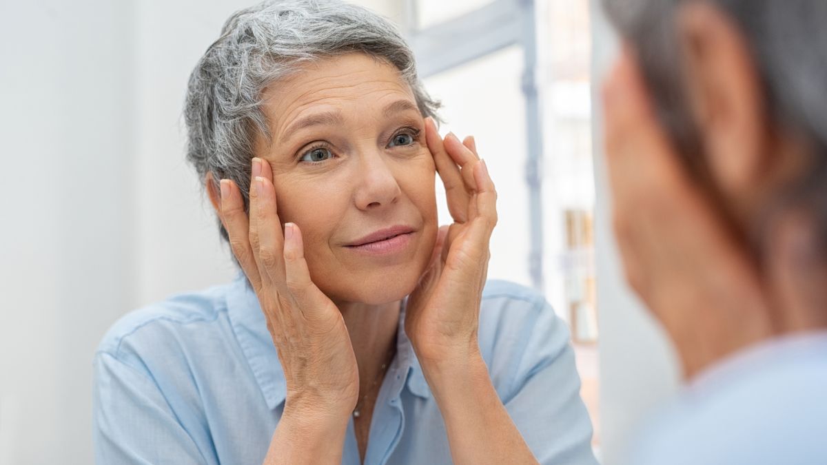 woman looking at forehead wrinkles in mirror