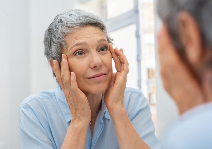 woman looking at forehead wrinkles in mirror