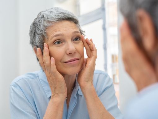 woman looking at forehead wrinkles in mirror