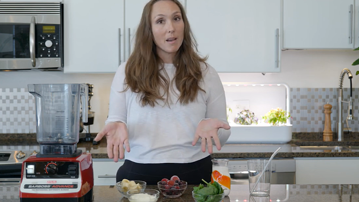 Woman in kitchen with blender making smoothie