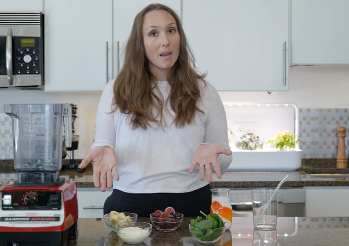 Woman in kitchen with blender making smoothie