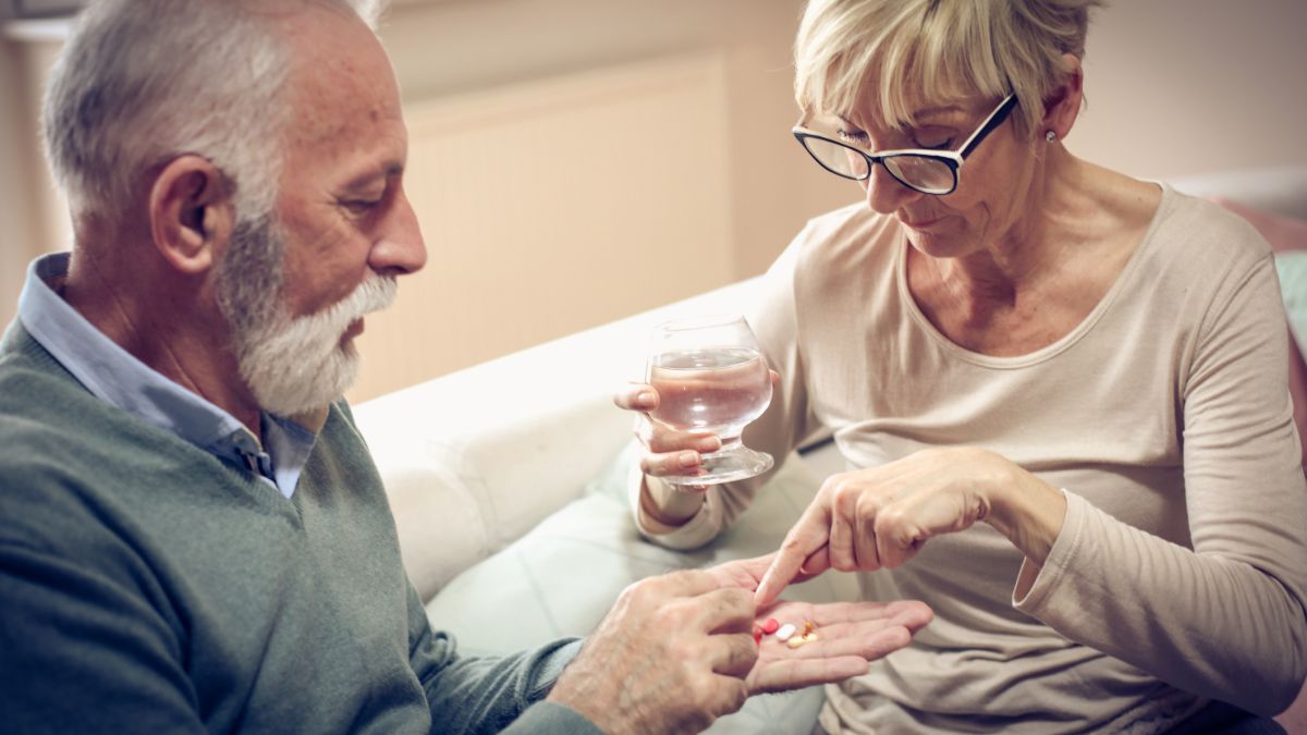 man with high blood pressure taking medicine given by his wife