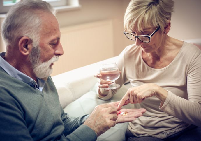 man with high blood pressure taking medicine given by his wife