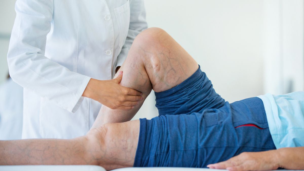 Doctor examining a patient’s leg while the patient lies on an exam table