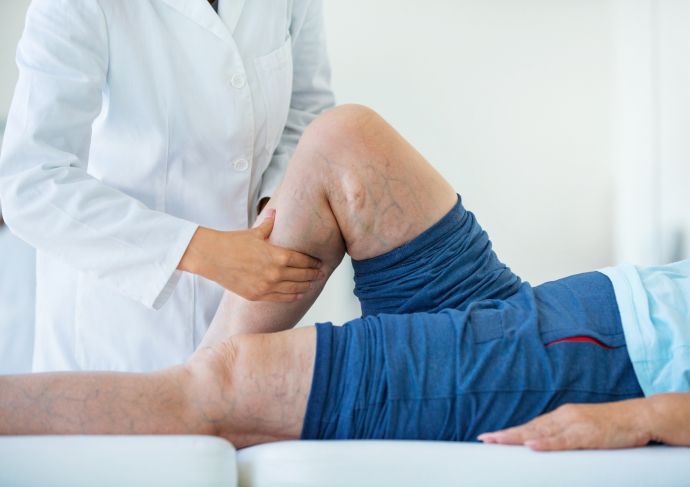 Doctor examining a patient’s leg while the patient lies on an exam table