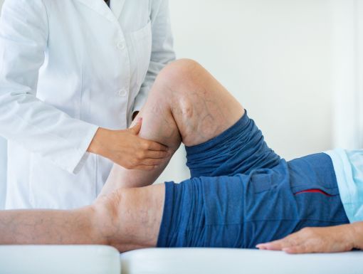 Doctor examining a patient’s leg while the patient lies on an exam table